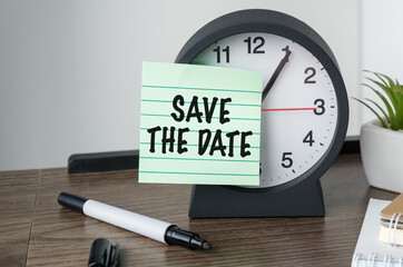 Save The Date text with alarm clock flat lay on wooden background