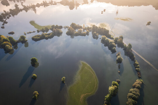 Aerial view of the flooded landscape reflecting the sky, with verdant patches and tree lines breaking the dark waters, Planina, Postojna, Slovenia.