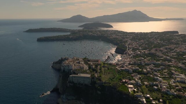 Aerial view backwards over the town on the Procida island, sunny evening in Italy