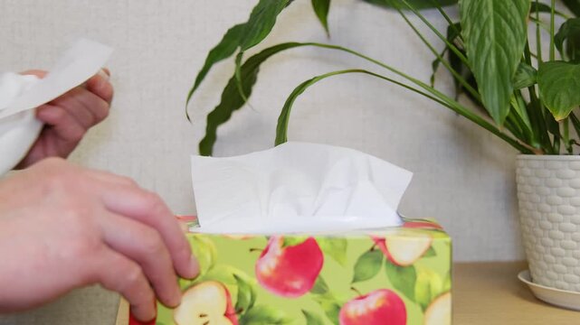 Soft tissue being gently pulled from container, Person carefully pulls tissue from apple box with background scene