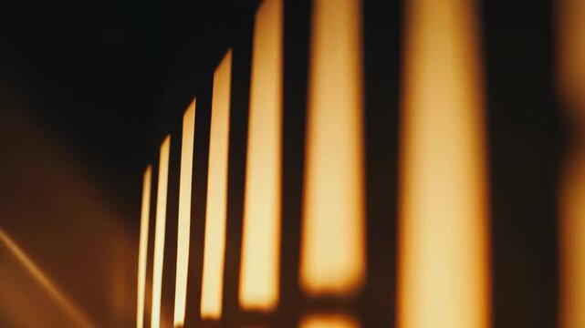 Warm sunlight projects abstract geometric grid patterns and diagonal lines onto a plain wall, creating a captivating interplay of light and shadow, evoking feelings of calm and simplicity