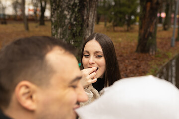 Young couple eating cotton candy on park bench 