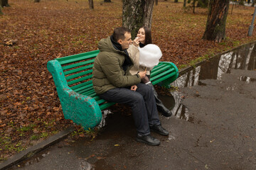 Young couple eating cotton candy on park bench 