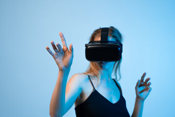 Young woman wearing virtual reality headset and interacting with digital interface using hand...
