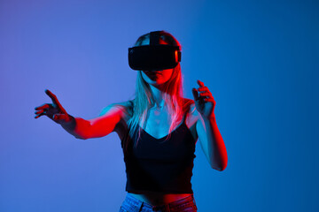 Woman using virtual reality headset and pointing in air, futuristic interaction with digital...