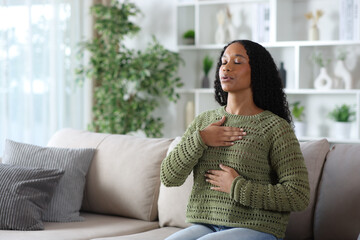Black woman in green doing breathing exercise at home