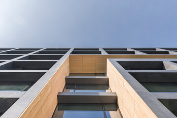 Nowoczesna fasada biurowca z geometrycznymi elementami z kamienia i szkła na tle nieba © ErOn