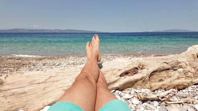 Man sunbathing on a rocky sea ocean beach.