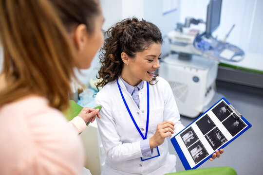 Pregnancy checkup with gynecologist using ultrasound. Professional female doctor consulting pregnant woman in medical clinic for prenatal care, sonography exam, and maternal health screening.
