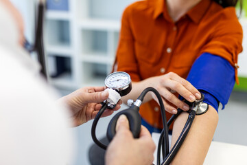 Close up of doctor checking blood pressure with manual gauge and stethoscope. Professional medical examination for hypertension and cardiovascular health monitoring in modern clinic.