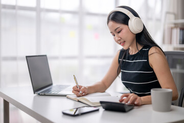 Young woman studying with headphones at home
