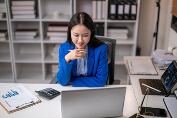 Asian businesswoman working with laptop and financial chart at office desk
