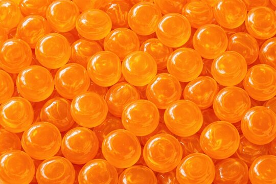 Close-up view of numerous glossy orange marbles arranged closely together, showcasing their smooth surfaces and vibrant color in a detailed composition