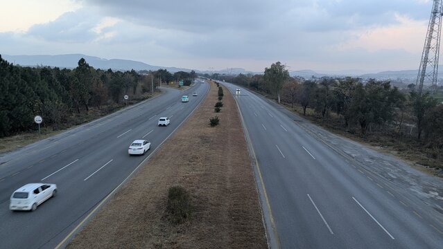 A beautiful winding road going through a patch of green trees on each side.Kashmir Road near Chattar Park, Punjab, Pakistan (01-23-2026) car and trafice View of Ring Road, Ring Road interexchange Isla