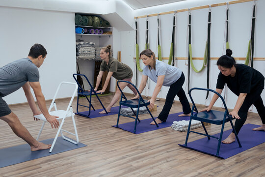Group of people using chairs at recovery Iyengar yoga class indoor
