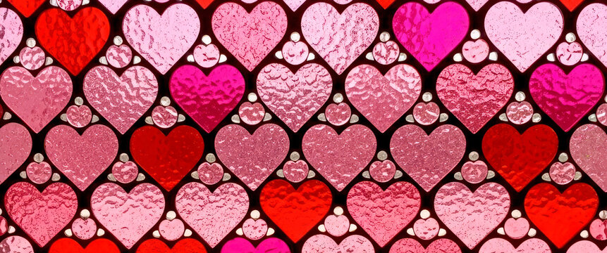 Stained glass mosaic window made from pink and red heart shaped details as a background. Valentine&rsquo;s Day, love, wedding concept banner for design.