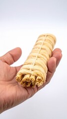 Person Holding bundle of uncooked ramen noodles tied with rubber band against a clean white background studio lighting