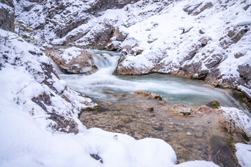 The Gleiersch Gorge in winter with snow, ice, and hanging icicles.