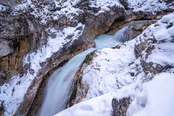 The Gleiersch Gorge in winter with snow, ice, and hanging icicles.