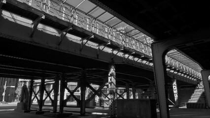 都会の鉄道高架下に広がる重厚な鉄骨構造と差し込む光が作るドラマチックな陰影