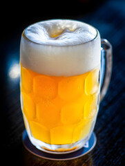 Close-up of a frosty glass mug filled with golden beer and frothy white head