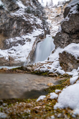 The Gleiersch Gorge in winter with snow, ice, and hanging icicles.
