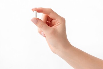 Hand holding white capsule pill isolated on clean medical background