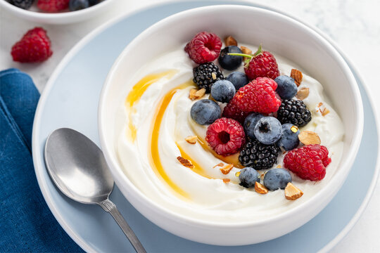 Greek yogurt  bowl with raspberries, blackberries, blueberries, almonds, and honey for breakfast. Healthy food. Close-up.