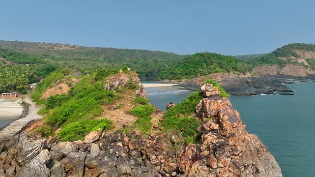 Drone footage of peaceful Konkan coastline , rocky beach, calm sea waves,  scenic natural beauty and tranquil environment in western India