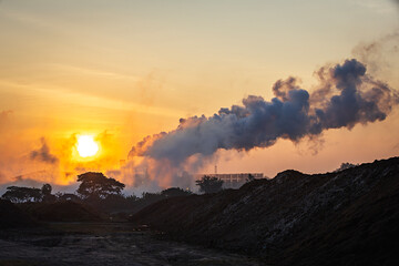 Fototapeta premium Smoke emissions from chimneys and industrial waste contributing to air pollution at sunrise, which pollutes environment and destroys the ecosystem.