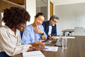 Obraz premium Female lawyers reviewing legal documents and discussing strategies while seated beside businessman in boardroom