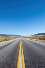 Endless open road through vast desert landscape under clear blue sky