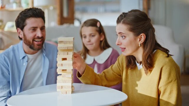 Playful family play game together building tower from blocks in cozy living room