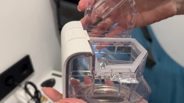 Woman demonstrating the water level in a CPAP machine's humidifier chamber. Emphasizes correct use, maintenance, and sleep apnea therapy. Themes: healthcare and user guide.