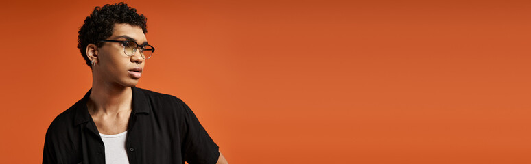 Obraz premium Stylish young man with eyeglasses poses in vibrant studio setting