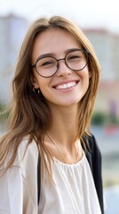 Portrait of a confident young woman with glasses smiling in front of blurred cityscape on a sunny day 