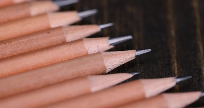 a group of wooden pencils with a black lead on a black pine , stacked pencils made of wood and a lead made of graphite