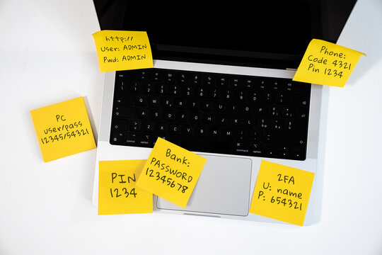 Multiple Unsafe Passwords and Login Credentials Written on Yellow Sticky Notes attached on a laptop
