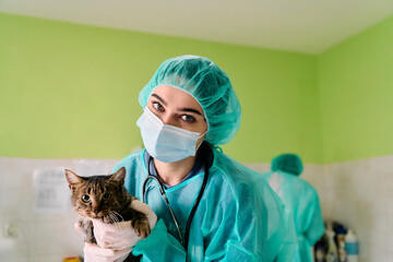 Vet In Protective Gear With Cat In Hand At Clinic Wearing Mask And Cap