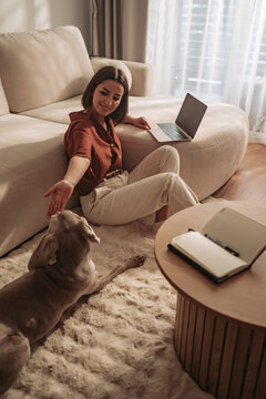A Woman Engaging Joyfully with Her Dog While Working from Home in a Cozy Atmosphere