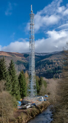 Obraz premium Futuristic modern vertical tower rising gracefully beside calm river in urban landscape