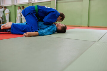 Two young athletes show their judo skills in front of the coaches
