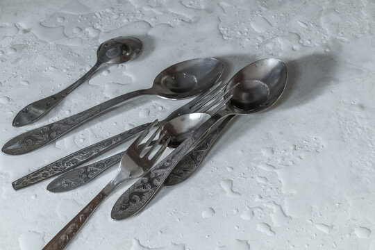 Wet tablespoons on a wet table. Essential items for everyday dining.