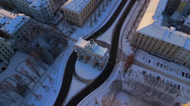Luftbild snowy city center in Germany. High angle view of Siegestor Victory Gate and Triumphbogen Triumphal Arch. Frosty Friedensmahnmal Peace Memorial in Bavaria Muenchen during winter travel season 