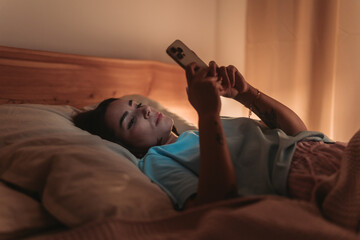 Fototapeta premium Woman Checks Email In Bed, Female Professional Works On Her Phone Amidst Restful Night Comfort