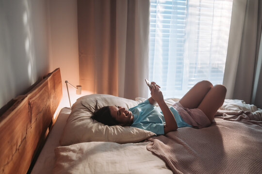 Genuine Lifestyle Depiction Of Woman In Sleepwear Engaging With Technology In Morning Sunlight