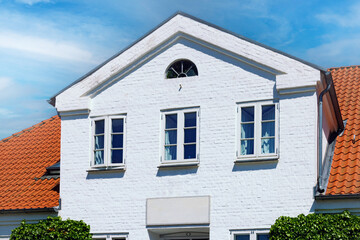 White brick house with red tile roof under blue sky