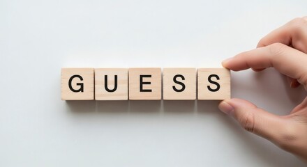 Guessing Game Hand arranges blocks spelling Guess on white backdrop.