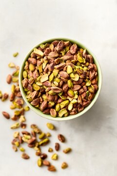 Pistachio nuts without shell in a bowl on a white marble background. Top view