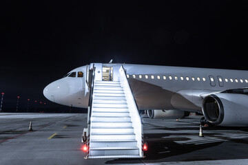 Modern passenger airliner with staircase at the night airport